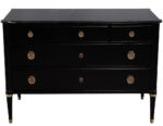 Antique-style black dresser with four drawers, brass hardware, and tapered legs, suitable as a statement nightstand.